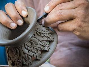 A person crafting a vase out of ceramics.
